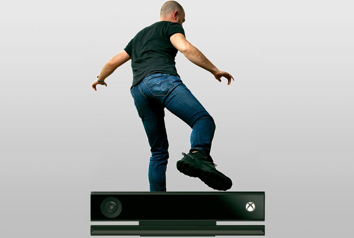 A man in jeans and a black t-shirt performing a motion capture on a digital scanning device, viewed from the back.