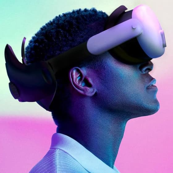 Side profile of a man wearing a VR headset, highlighted by a colorful pink and blue gradient backdrop, engaged in a virtual reality session.
