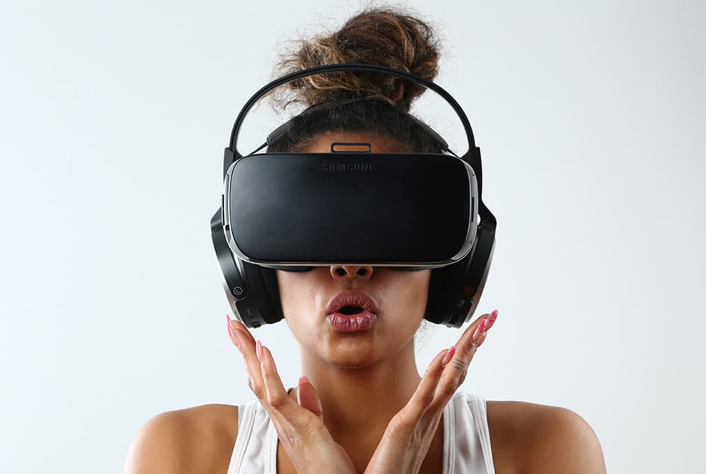 A woman wearing a virtual reality headset with a surprised expression, seemingly reacting to the content of the VR experience.