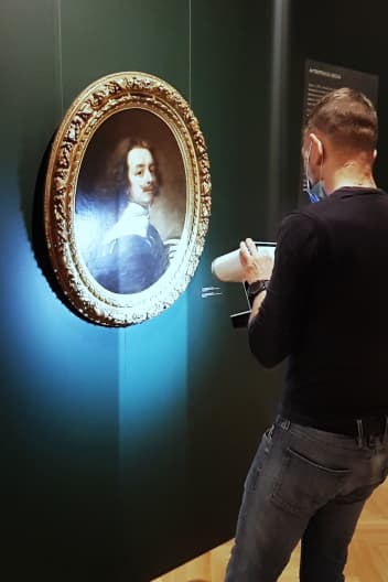 A person uses a 3D scanner on an oval-framed portrait from a past century