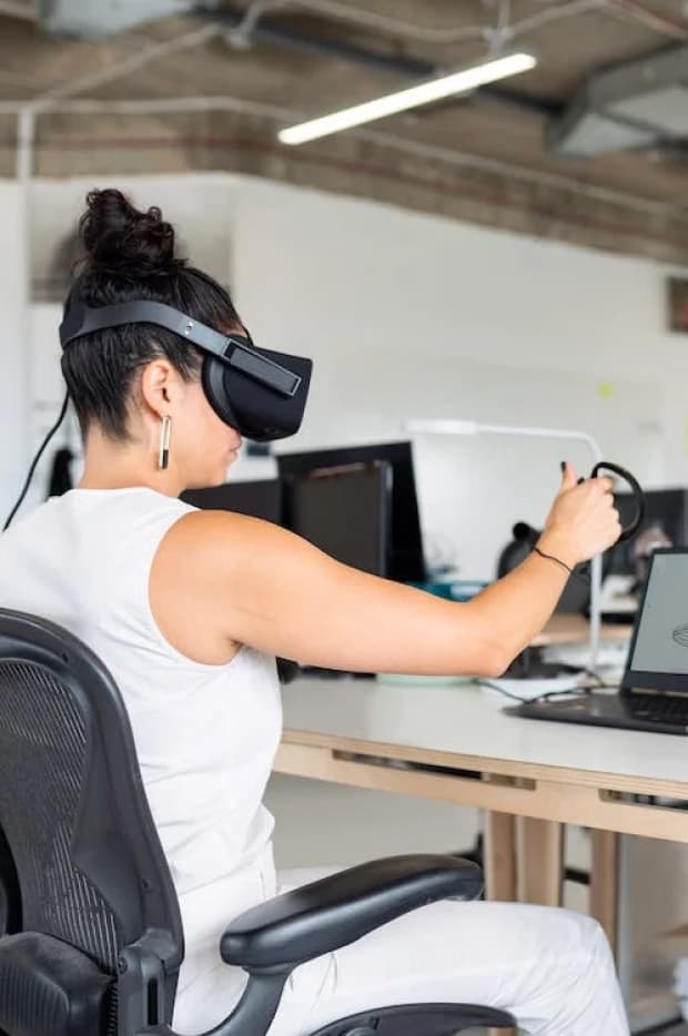 A person wearing a virtual reality headset and holding a controller, engaged in an immersive experience, possibly in a virtual meeting or simulation.
