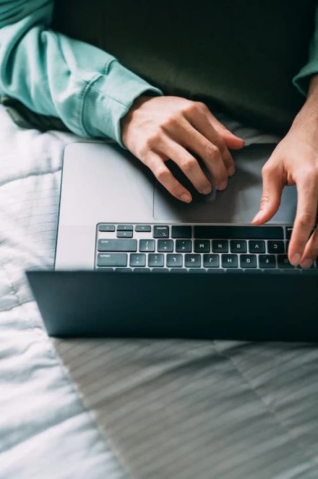 Close-up of a person's hands typing on a laptop keyboard, suggesting work, communication, or internet browsing, with a focus on the interaction between user and device.